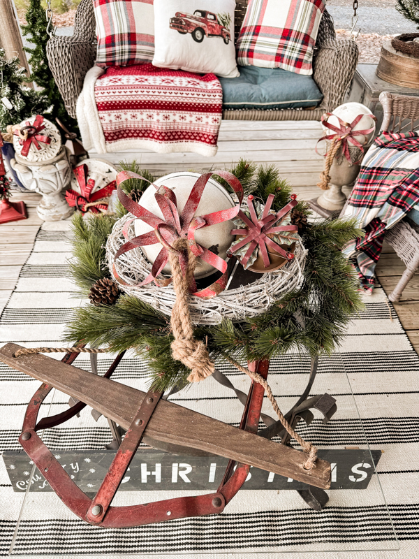 Vintage sled with thrifted wreaths and jingle bells for a coffee table centerpiece on Christmas Farmhouse porch.
