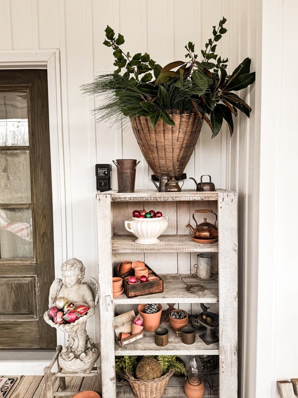 Rustic vintage cabinet with Christmas Decorations and a wall basket filled with fresh evergreen greenery.  