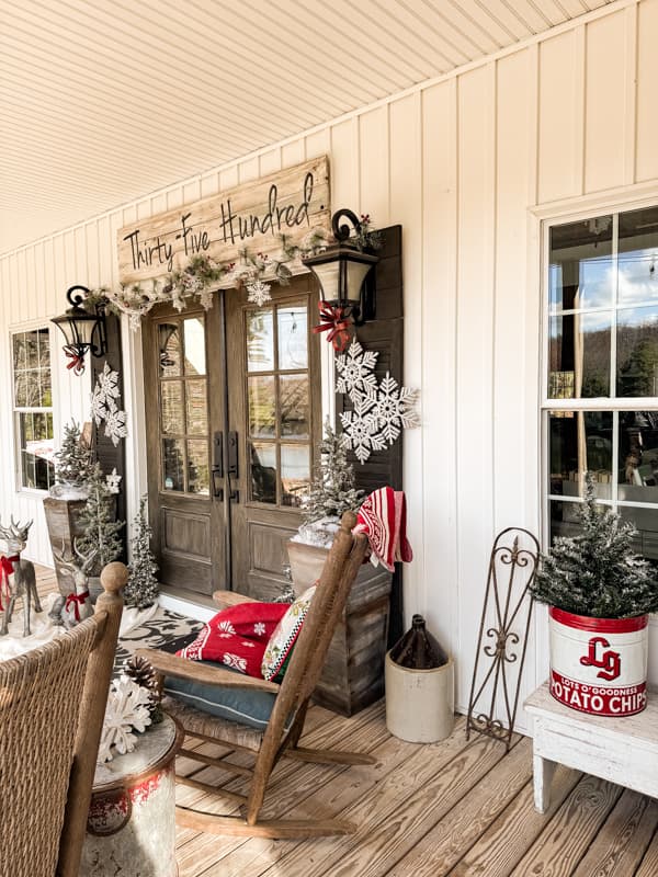 Farmhouse Country Porch decorated for Christmas with pops of red in a vintage potato chip tin. 
