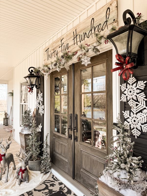 Cozy Christmas Front Porch with Winter Wonderland Decorations of snowflakes, red bows and faux garland.