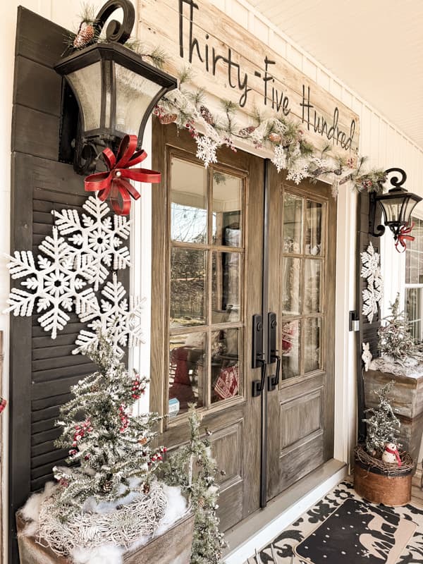 Cozy Christmas Front Porch with Winter Wonderland Decorations of snowflakes, red bows and faux garland.