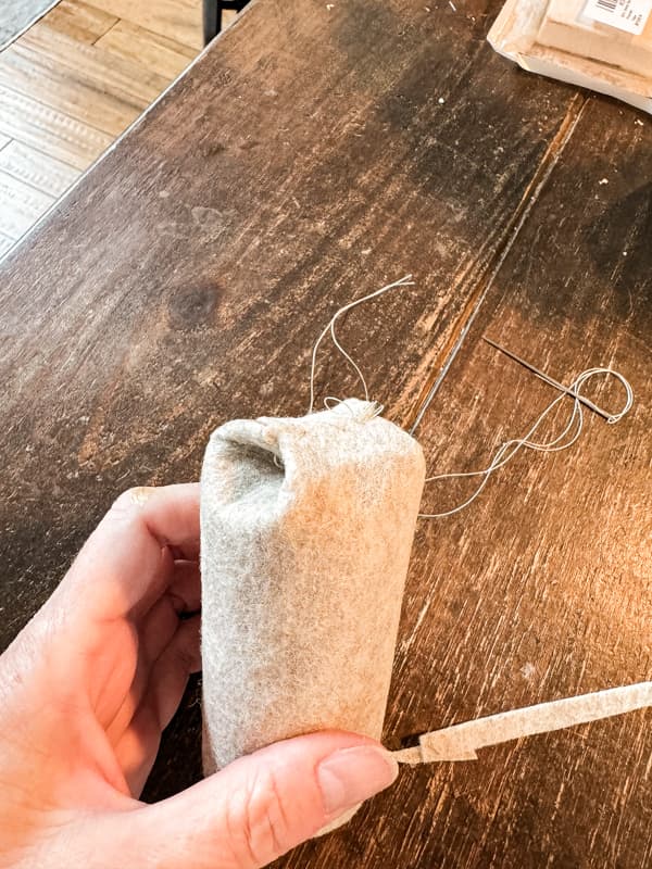 Stitch the felt fabric down at top of recycled toilet paper roll for DIY Christmas Decorating Project.