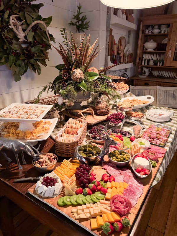 Annual Christmas Party Table 2023.  Greenery and Feather Centerpiece with Charcuterie Boards and budget appetizers.  