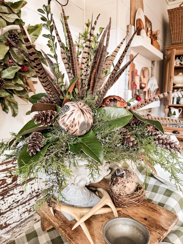 Christmas Party Table Centerpiece with feathers and natural greenery. Cedar, Magnolia and Boxwood