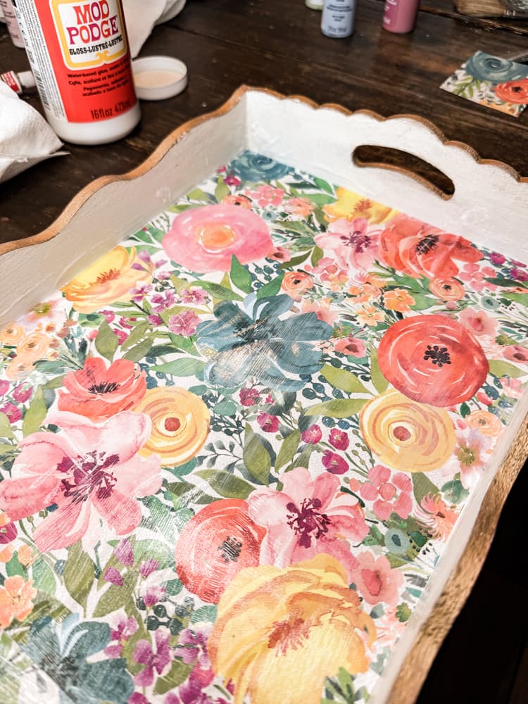 Add decorative scrapbook paper with flowers to bottom of decorative tray with mod podge 