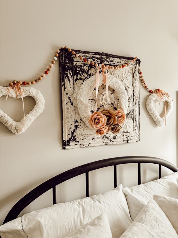 Old tin ceiling tile holds DIY Paper Rose Valentines Wreaths in guest bedroom 