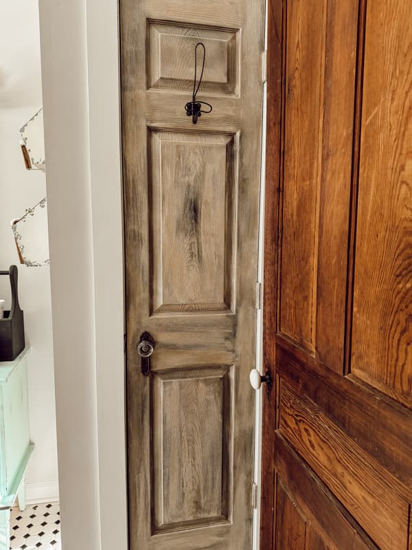 Closet door with faux antique finish in bathroom of modern farmhouse.  