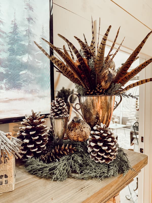 Silver urn filled with pheasant feathers and pinecones for a Winter Mantel decorations.