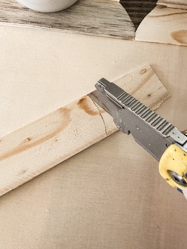 score the wood shims with a utility knife to get the heart shape for a primitive heart hanger.
