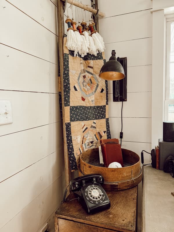 Family heirloom antique quilt hanging on a vintage ladder with wooden spool tassel garland. 
