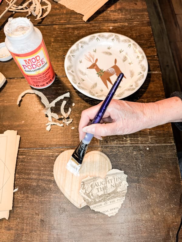 Add mod podge to wooden heart for rustic Valentine's Day Project.