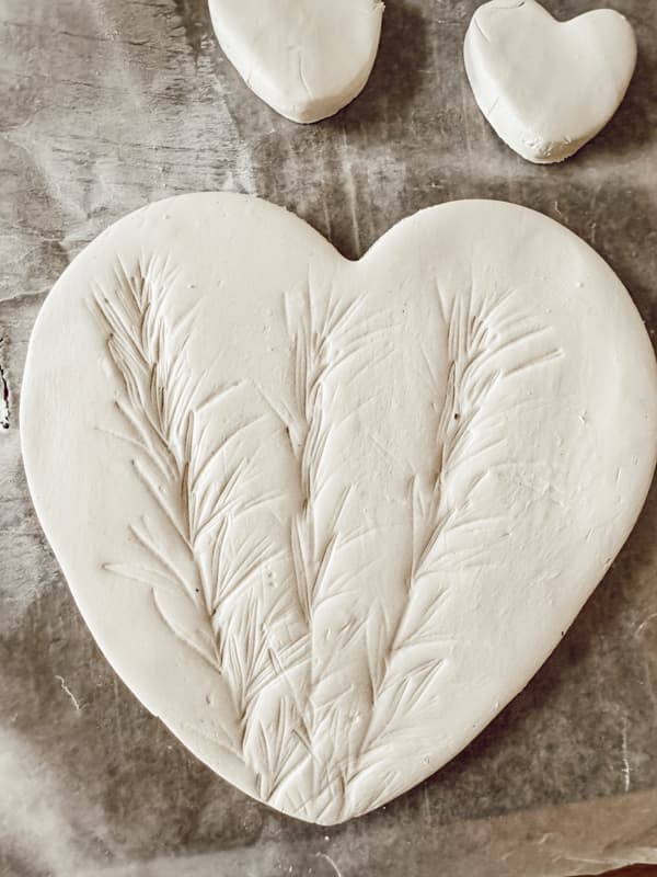 add design to clay hearts with rosemary sprig.  