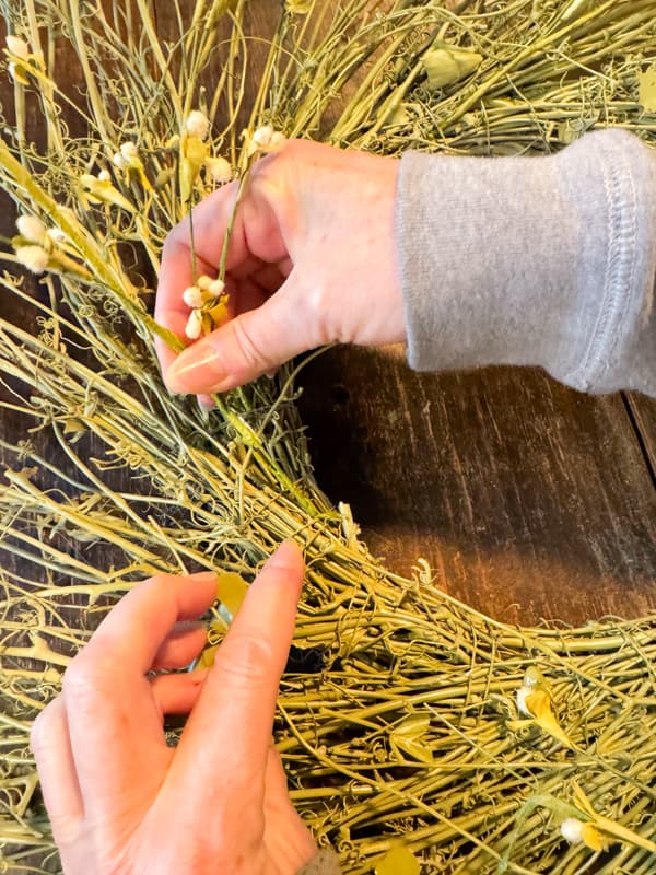 Add flower stems to upcycled grapevine wreath with hot glue.