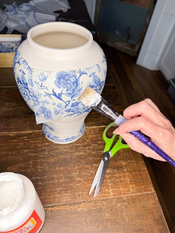 Press the blue and white napkins pieces onto the painted jar.  Smooth gently with the mod podge brush. 