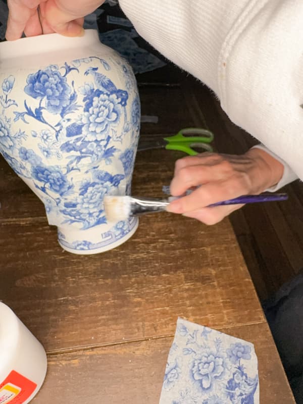 Press the blue and white napkins pieces onto the painted jar.  Smooth gently with the mod podge brush. 