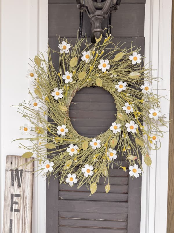 Anthropologie Inspired Spring Wreath with White and yellow flowers on front porch black shutter. 