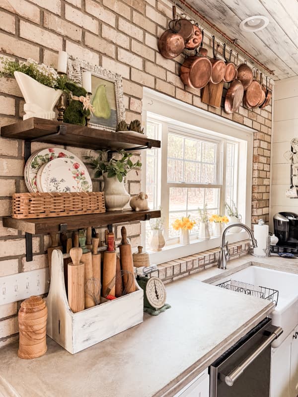Farmhouse Kitchen with DIY Concrete Countertops and open shelving against a brick wall.  