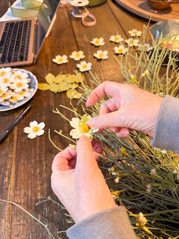 Adhere upcycled aluminum can flower  to wreath with hot gluel