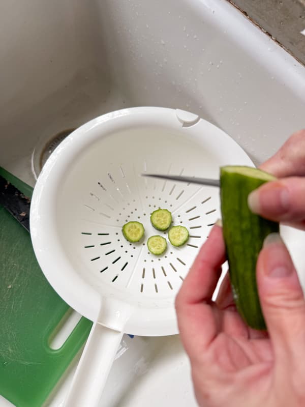 Slice cucumbers into colander.