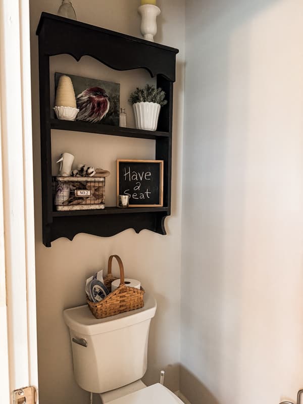 thrift store black sheving unit over toilet in modern bathroom.  