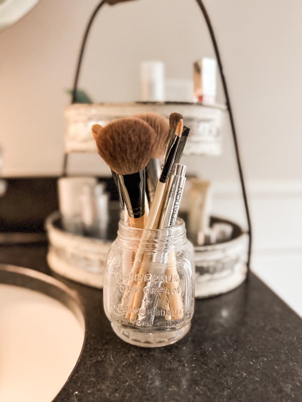 antique glass jar filled with makeup brushes for modern bathroom vintage decor ideas.  