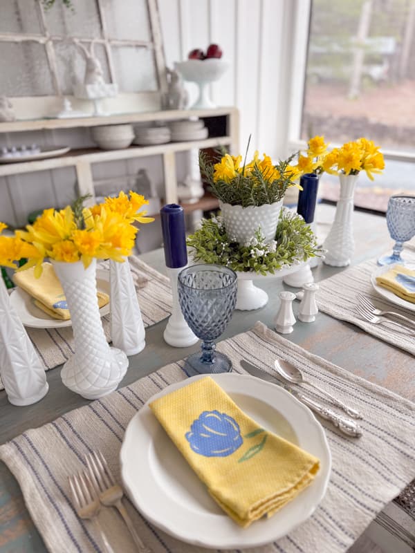 milk glass bud vases filled with fresh daffidols and blue and white accessories for Table centerpiece ideas. 