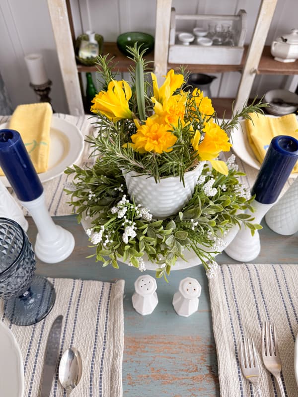 milk glass hobnail vase filled with fresh daffidols and blue and white candles for Table centerpiece ideas. 