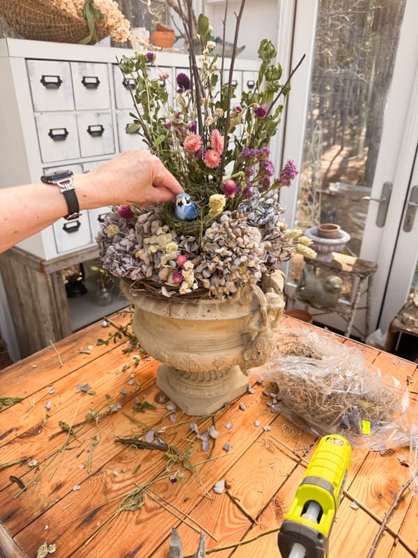 Add a faux bird and nest to the center of the arrangement.