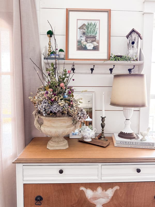 Dried Flower arrangement with hydrangeas, bird nest, gathered twigs and grapevine on farmhouse entry table. 