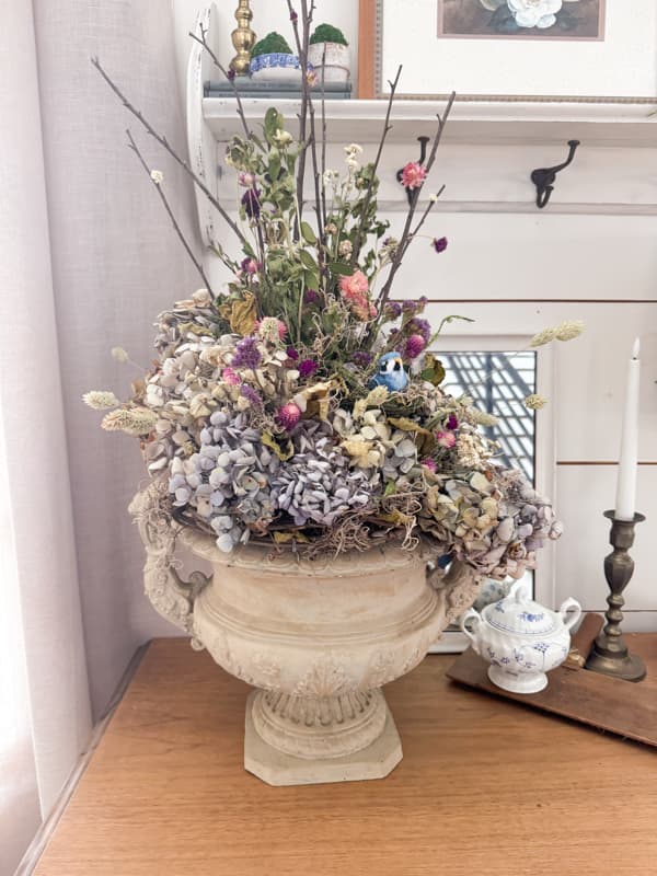 country chic decorating with dried flowers in a large urn on entry table with bird nes and foraged twigs and grapevine.  