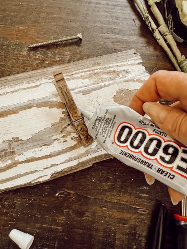 Use e6000 glue to adhere clothespins to the old wood board.  