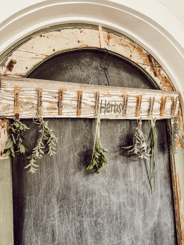 Herb drying rack with clothespins hanging on chippy pantry door.  