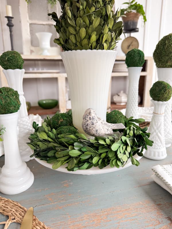 Green moss balls and preserved boxwood topiary and wreath mixed with vintage decor for a summer centerpiece