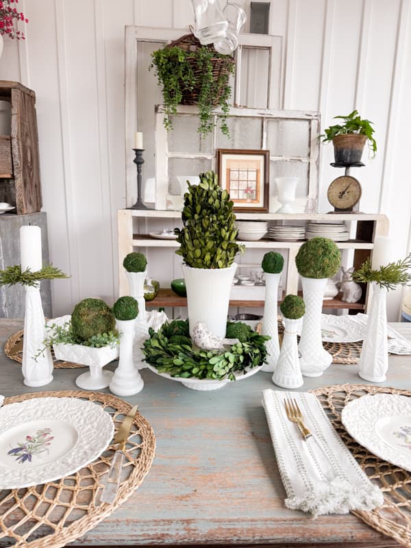 Green moss balls and preserved boxwood topiary and wreath mixed with vintage milk glass for a summer centerpiece.