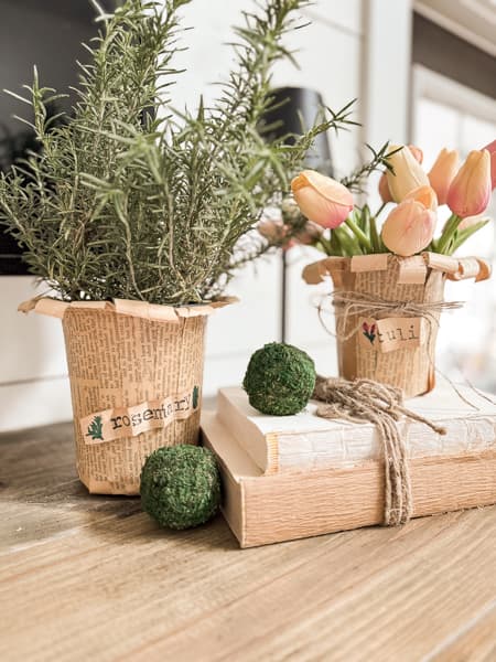 Decorating with DIY Flower Pots filled with fresh rosemary and faux tulips on deconstructed old books and moss balls on mantel 