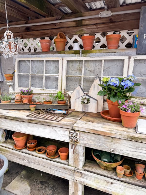 Rustic potting bench with container garden ideas for a rustic outdoor decor with reclaimed old windows and solar chandelier.  