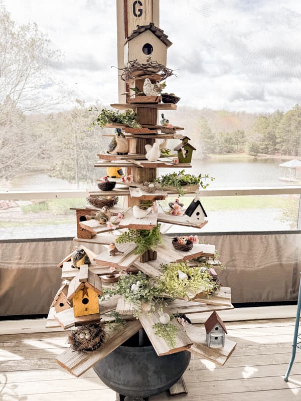 Shiplap tree with thrift store birdhouse topper and bird nest and birds filled reclaimed shiplap branches.