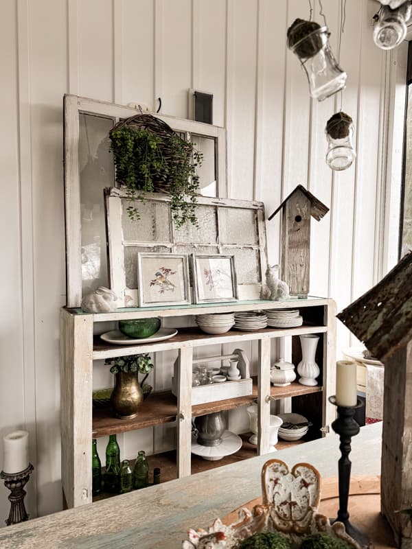 Needlepoint birds and birdhouse with reclaimed old windows on sideboard.