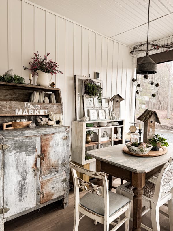 Screen porch dining table with vintage metal icebox and farmhouse table with spring decor.  