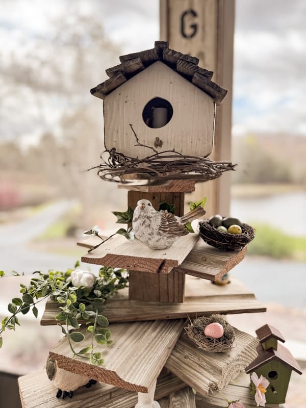 Shiplap tree with thrift store birdhouse topper and bird nest and birds filled reclaimed shiplap branches.