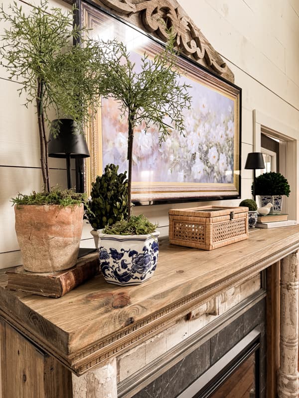 Rustic blue and white flower containers with topiaries and rattan box for Farmhouse Springtime Mantel decor