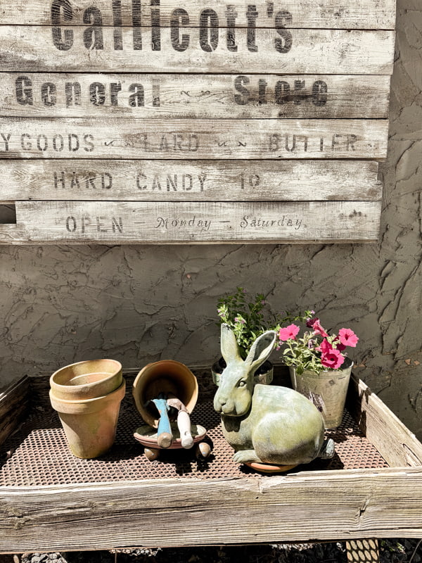 Vintage sign with concrete statue bunny for outdoor vignette.