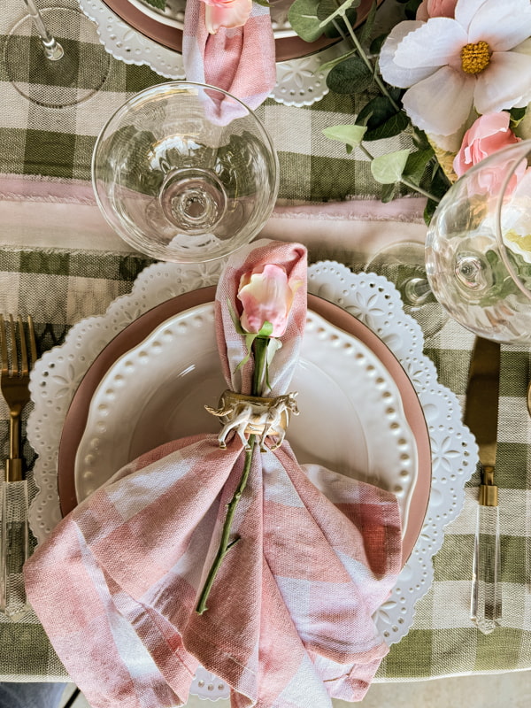 Pink and white buffalo print napkins with DIY horse napkin rings and a pink rose on the center of each plate.