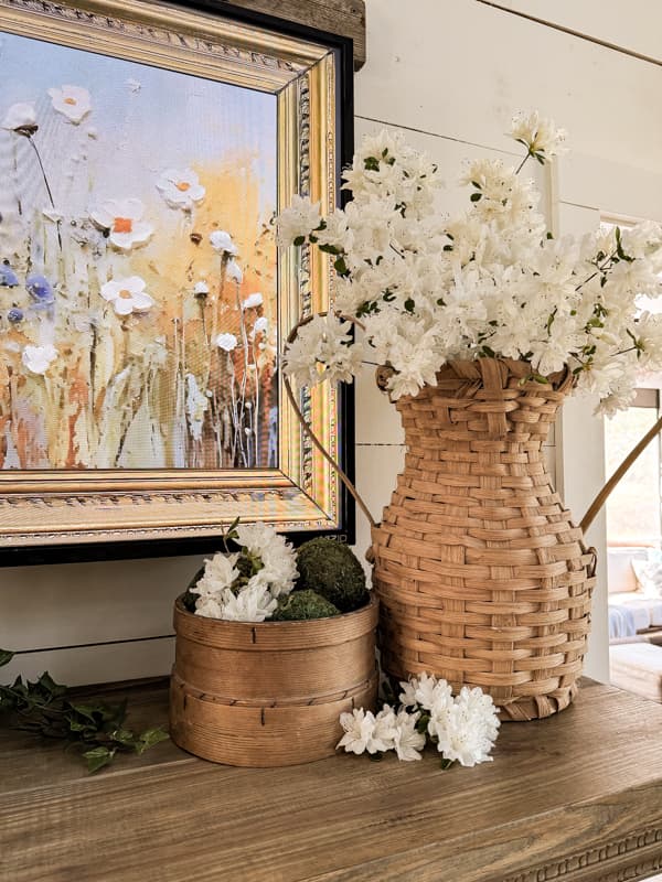 Thrift Store Basket Vase filled with fresh white azaleas on Spring Mantel with wooden shifter filled with moss balls. 