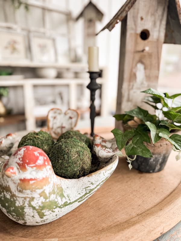 Centerpiece on farmhouse table with  birdbath and  with pot of ivy.