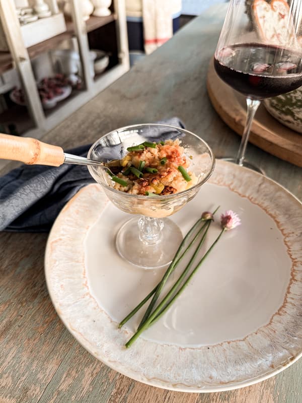 Parmesan Crusted Baked Oyster Casserole Recipe in compote dish with chopped chives and bamboo fork. 