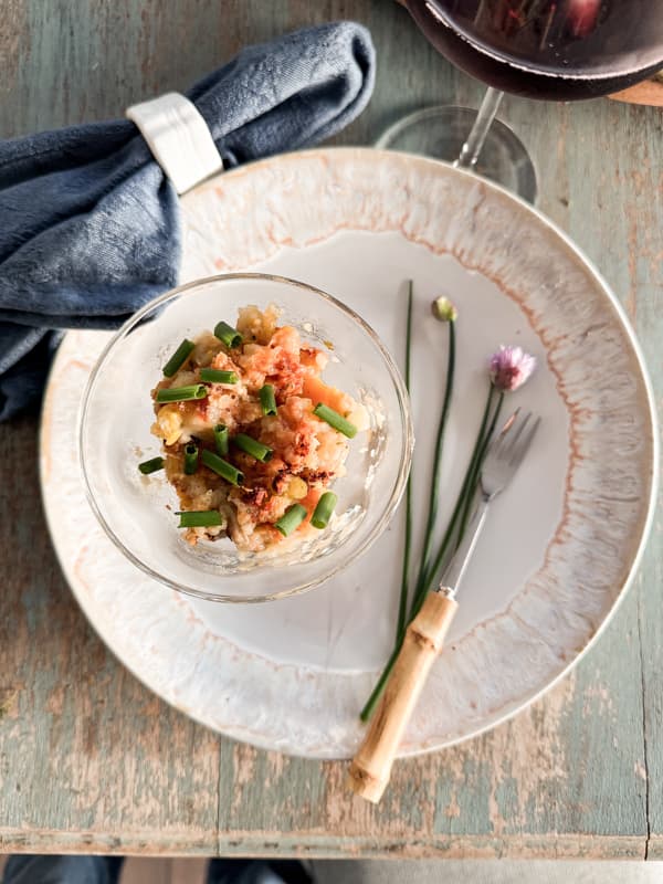 Parmesan Crusted Baked Oyster Casserole Recipe in compote dish with chopped chives and bamboo fork. 