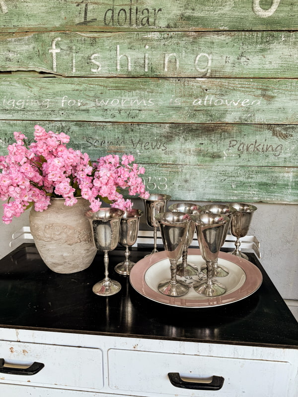 Silver goblets and pink azaleas on side cabinet for mint juleps.  