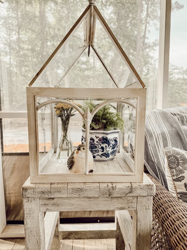 DIY Terrarium with fern plant in blue and white container with bird and vase of yarrow flowers.