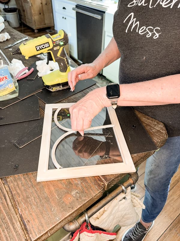 Attach architectural arches cut from the garden fence to the glass on picture frames with hot glue to make a DIY Glass Terrarium.